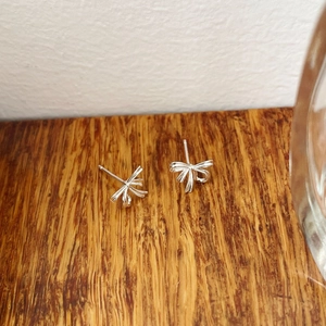 Gros plan de petites boucles d'oreilles nœud en argent sterling S925 sur fond de bois