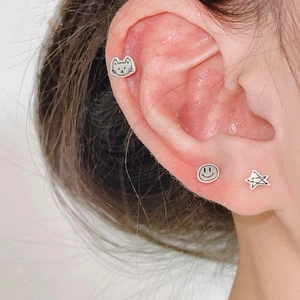 Vue macro de boucles d'oreilles S925 en argent avec smileys et étoiles portées