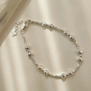 Détail d'un bracelet en argent S925 avec breloques en forme de cœur et perles texturées