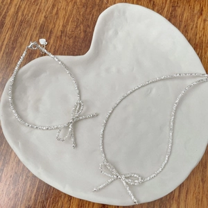 Macro detail of silver bow bracelet with crushed silver texture on a heart-shaped plate