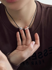 Détail du collier de perles en cristal noir avec pendentif cœur et accents argentés