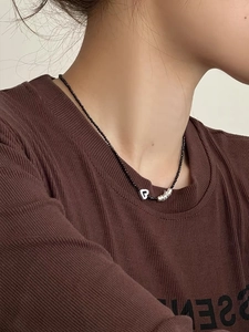 Gros plan d'un pendentif coeur en argent S925 sur un collier de perles noires minimaliste