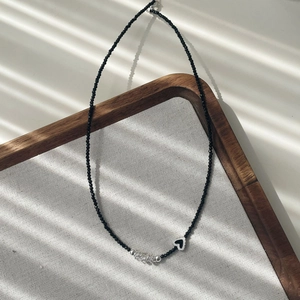 Vue macro du pendentif coeur en argent S925 et collier de perles noires sur un plateau