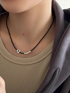 Détail du pendentif cœur sur collier de perles noires en argent S925 sur un mannequin