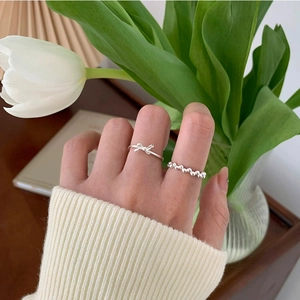 Silver hollow bow and bead ring set worn by model in a cozy minimalist home setting