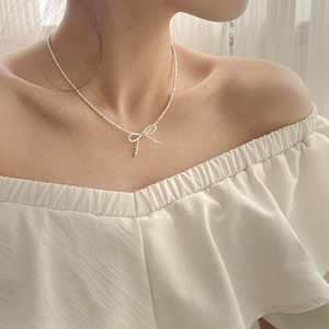 Close-up of S925 sterling silver bow pendant necklace worn by a female model