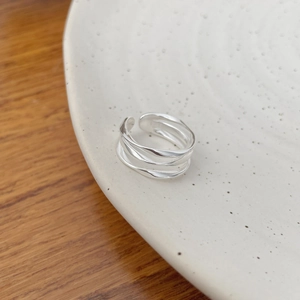 Vue détaillée d'une bague vague argentée à trois couches sur un plateau en céramique