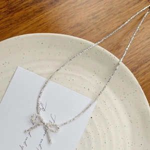 Close-up of S925 silver irregular bow bracelet on a ceramic plate with warm lighting