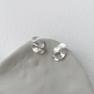 Dettagli macro di orecchini geometrici in argento S925 con finitura opaca sabbiata