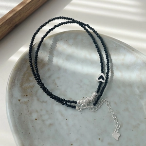 Détail du pendentif cœur en argent S925 et perles de spinelle noire sur une assiette