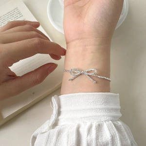 Close-up of S925 silver bow bracelet on model wrist in a minimalist lifestyle setting