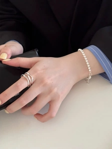 Détail de bague argentée irrégulière et bracelet à billes sur la main du modèle