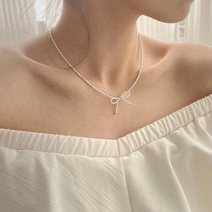 Close-up of S925 silver bow necklace on model's neck with delicate sparkling chain