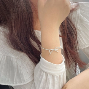 Close-up of S925 silver bow bracelet on female wrist with delicate textured chain link