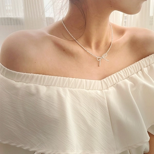 Silver bow necklace featuring sparkling zircons worn by a model on the collarbone