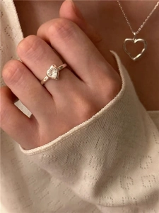 Gros plan d'une bague coeur en argent S925 avec zircone et collier assorti sur un pull