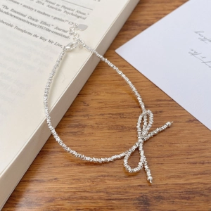 Detailed shot of S925 silver bow bracelet with crushed silver beads on wood background