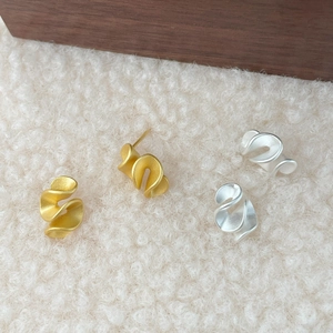 Dettaglio di orecchini in argento S925 con finitura opaca e design a gonna plissettata