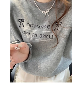 Close-up of gray sweatshirt with Romantic Long Island print and black bow detail