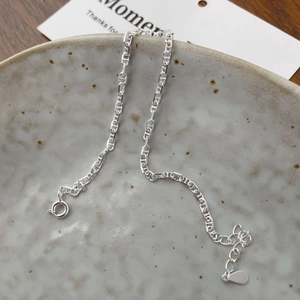 Détail du bracelet chaîne à maillons nez de cochon S925 sur une assiette en céramique
