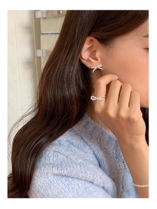 Detailed view of pearl woven bow earrings and matching open ring set worn by model