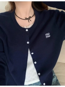 Detail of navy knit cardigan with contrast white buttons and logo embroidery
