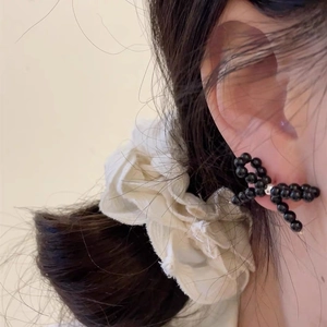 Close-up of handmade black beaded bow earrings worn on model for delicate daily wear