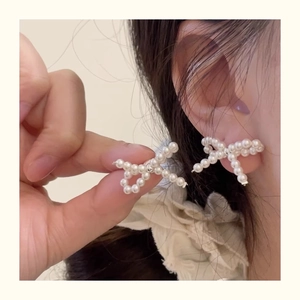 Detailed view of woven pearl bow earrings in a minimalist 925 sterling silver design
