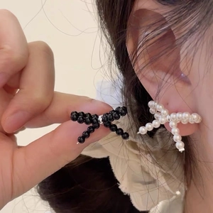Detailed view of handmade bow-shaped beaded stud earrings with black and white pearls