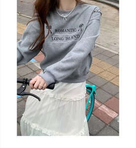 Outdoor street style shot of a woman wearing a delicate silver pearl bow necklace