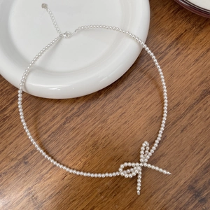 Detailed view of cream pearl necklace featuring a woven bow and adjustable lobster clasp