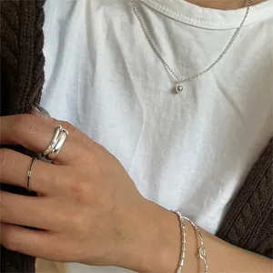 Détail du collier à pendentif boule en argent 925 et bagues portés par un mannequin