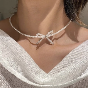 Detail of elegant S925 sterling silver bow pearl necklace worn on a female model neck