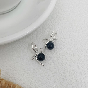 Detailed macro shot of S925 silver bow earrings with polished black agate beads