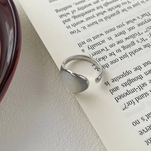Vue macro d'une bague en argent S925 avec pierre de nacre sur des pages de livre