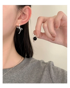 Detailed close-up of S925 silver bow earrings with polished black agate beads on model