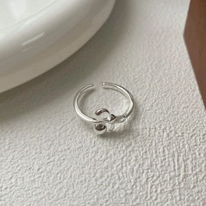 Anello a fiocco minimalista in argento S925 regolabile su sfondo materico bianco