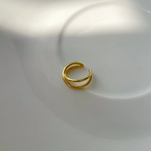 Close-up of minimalist double-layer crossover gold plated ear cuff on white display stand
