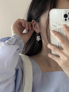 Close-up of S925 silver flower drop earrings showing polished 3D petals on ear