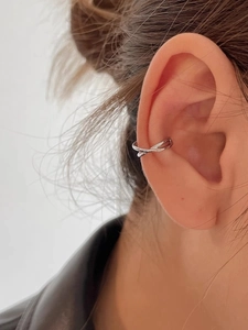 Close-up of minimalist S925 silver cross-over ear cuff on female model ear