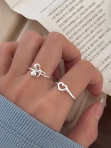 Dettaglio del set di anelli con fiocco in argento S925 e cuore traforato sulla mano