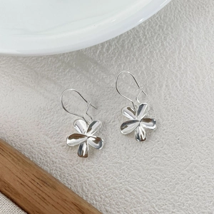 Detail view of silver S925 flower petal earrings on minimalist textured background