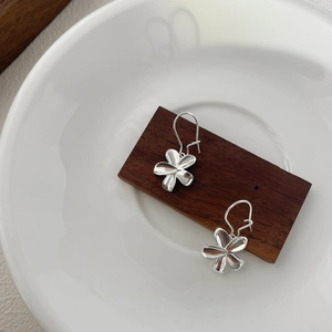 Detailed close-up of S925 silver flower earrings with polished petals on wooden display