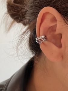 Detailed view of silver X-shaped multi-layer ear cuff on a female model ear