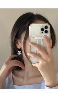 Close-up of silver S925 floral drop earrings with a polished mirror finish on model