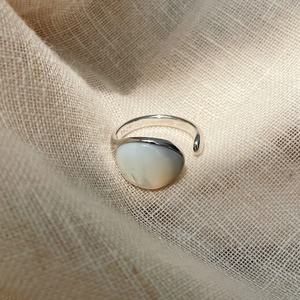 Détail macro d'une bague en argent S925 avec nacre ovale sur tissu en lin