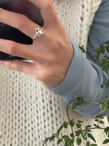 Anello a fiocco minimalista in argento sterling S925 lucido indossato su sfondo di maglia