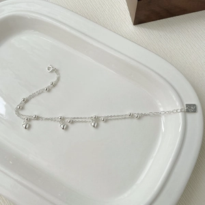 Vue macro détaillée du bracelet double couche en argent S925 avec breloques cœur et logo