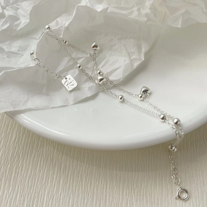 Détail du bracelet double couche en argent S925 avec cœurs sur une assiette blanche