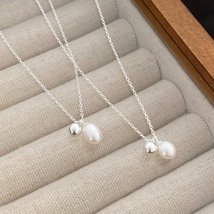 Macro detail of S925 silver necklace featuring a metal ball and teardrop pearl pendant